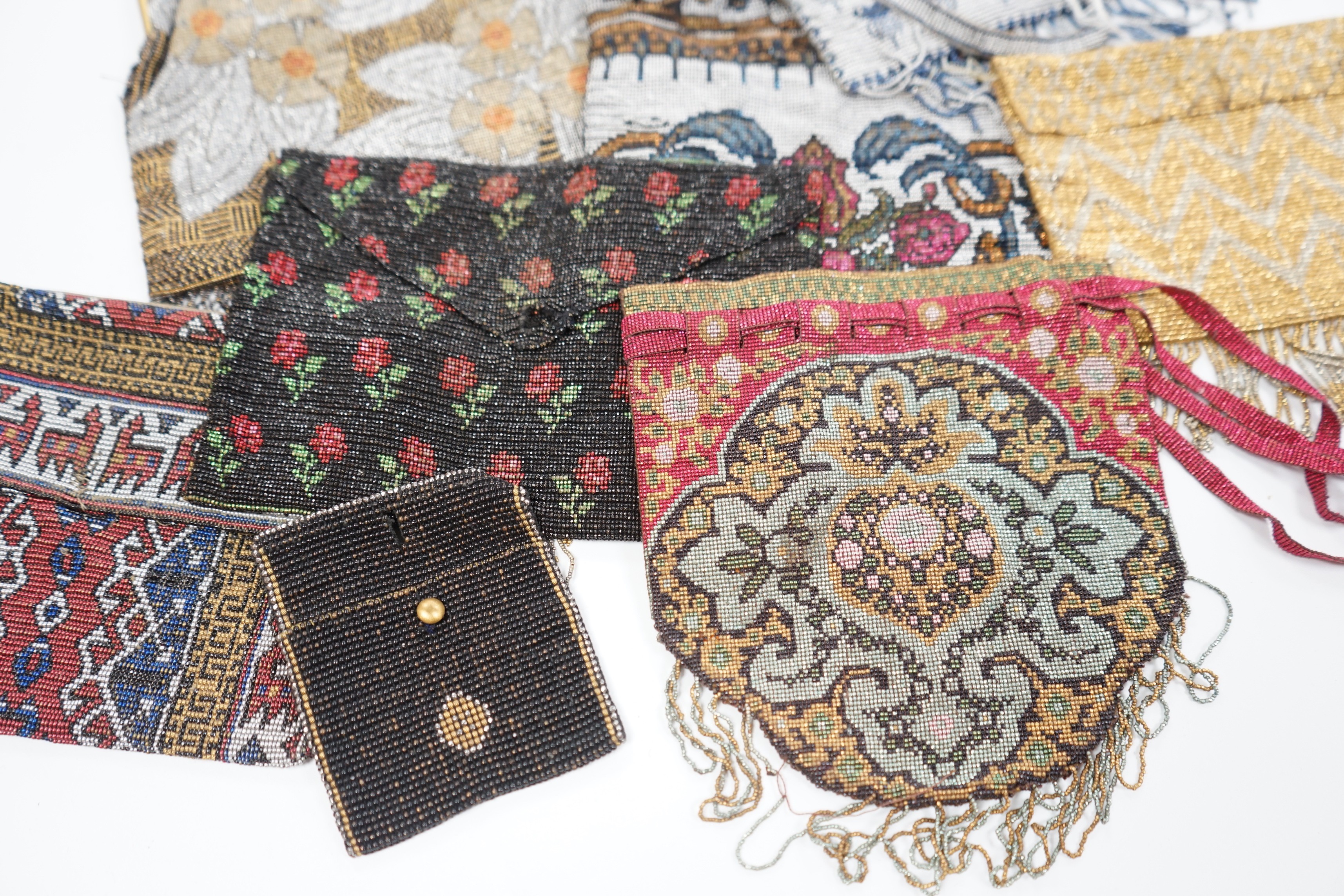 Seven late 19th century multicoloured and designed cut steel evening bags and a small coin purse (8)